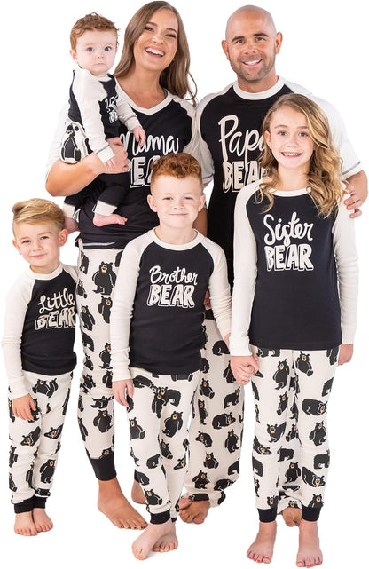 Family wearing matching black and white Family Bear pajamas with bear prints and labeled tops for mom, dad, sister, brother, and little bear baby.