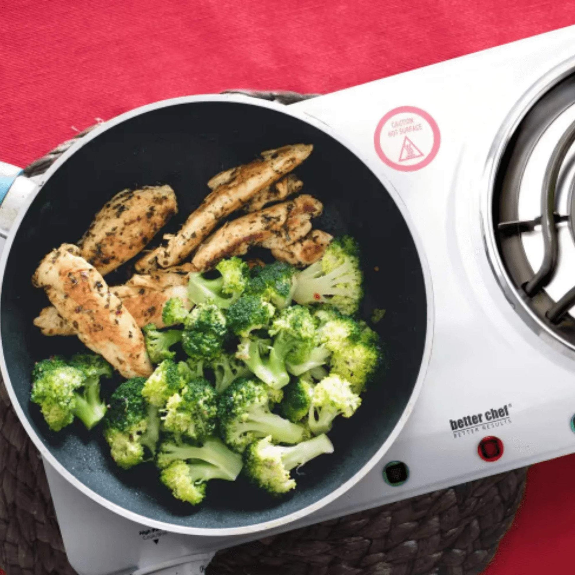 Better Chef Electric Countertop Double Burner cooking chicken and broccoli in a white enamel coil stovetop with temperature control knobs